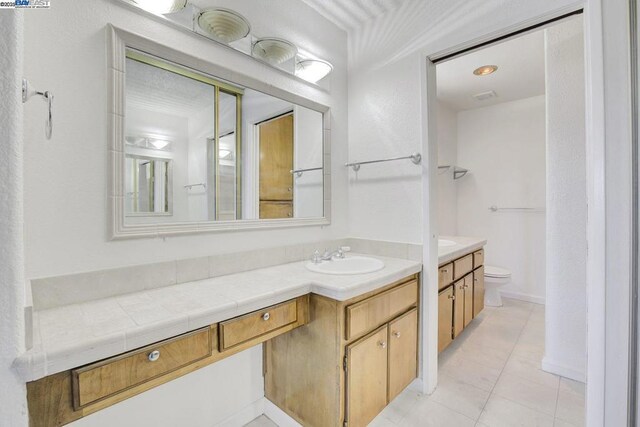 bathroom with toilet, vanity, and tile patterned flooring