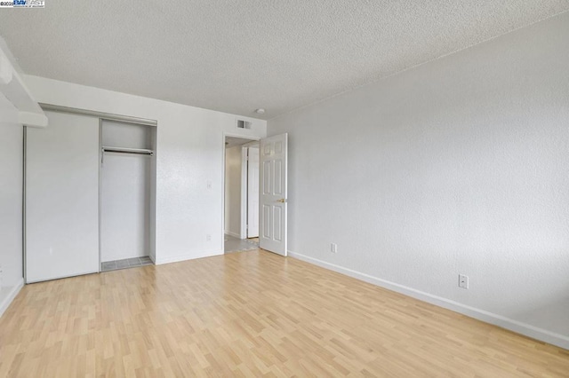 unfurnished bedroom with light wood-type flooring, a closet, and a textured ceiling