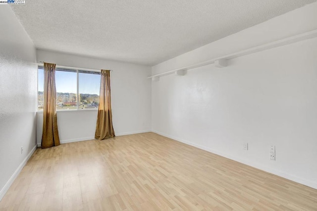 empty room with light hardwood / wood-style floors and a textured ceiling