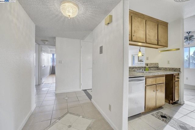 kitchen featuring stainless steel dishwasher, light tile patterned floors, sink, and a textured ceiling