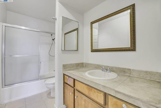 full bathroom featuring bath / shower combo with glass door, toilet, vanity, and tile patterned flooring