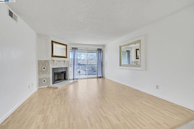 unfurnished living room with light hardwood / wood-style floors, a textured ceiling, and a fireplace