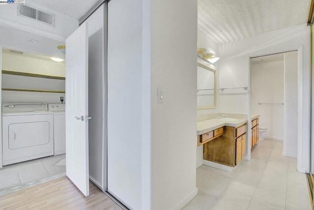 bathroom with washing machine and dryer, toilet, a textured ceiling, and vanity