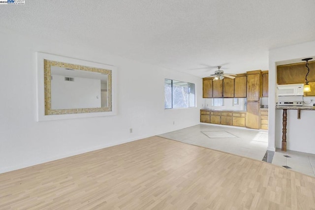 interior space featuring ceiling fan, a textured ceiling, and light hardwood / wood-style flooring