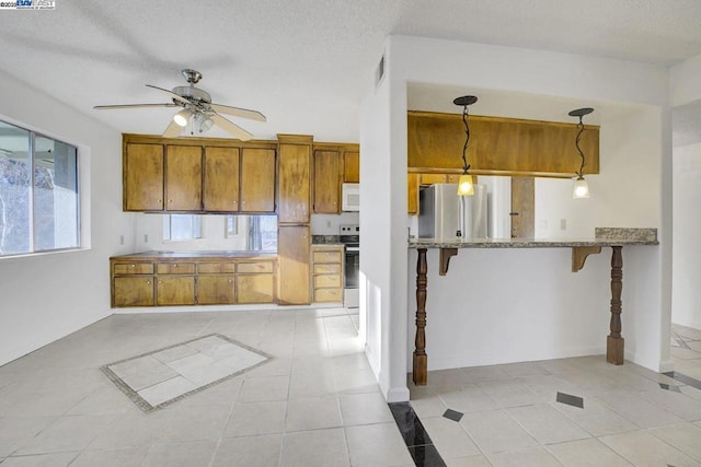 kitchen featuring light tile patterned floors, ceiling fan, appliances with stainless steel finishes, pendant lighting, and a breakfast bar