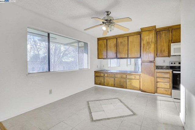 kitchen featuring ceiling fan, plenty of natural light, light tile patterned floors, and stainless steel range with electric stovetop