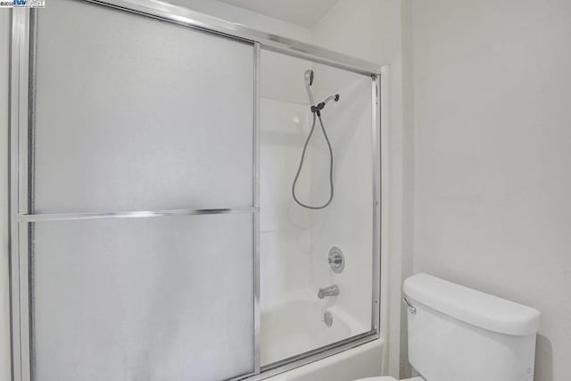 bathroom featuring toilet and combined bath / shower with glass door