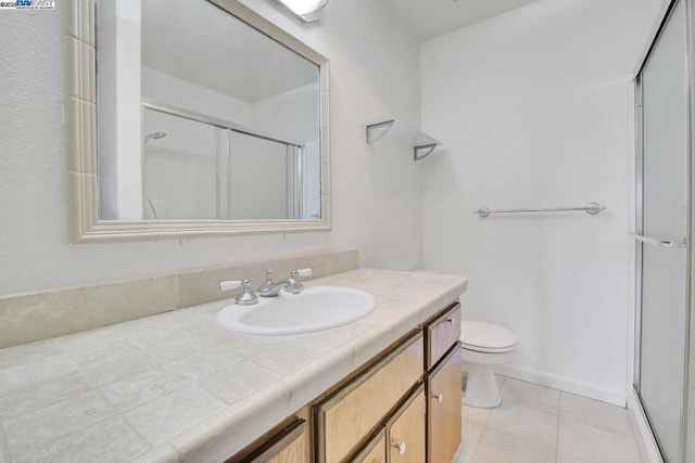 bathroom featuring toilet, vanity, tile patterned flooring, and walk in shower