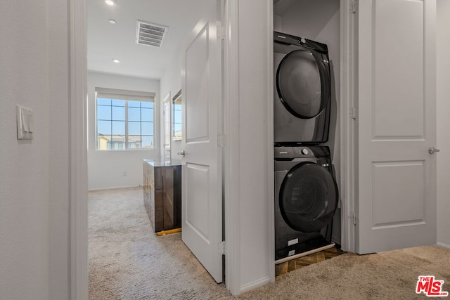 laundry room with light carpet and stacked washer / dryer