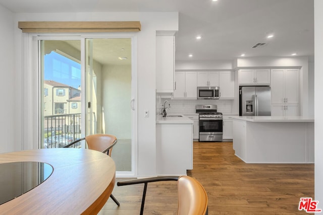 kitchen featuring white cabinetry, stainless steel appliances, tasteful backsplash, sink, and hardwood / wood-style flooring