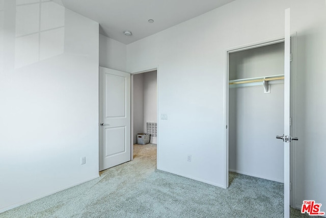 unfurnished bedroom featuring light carpet and a closet