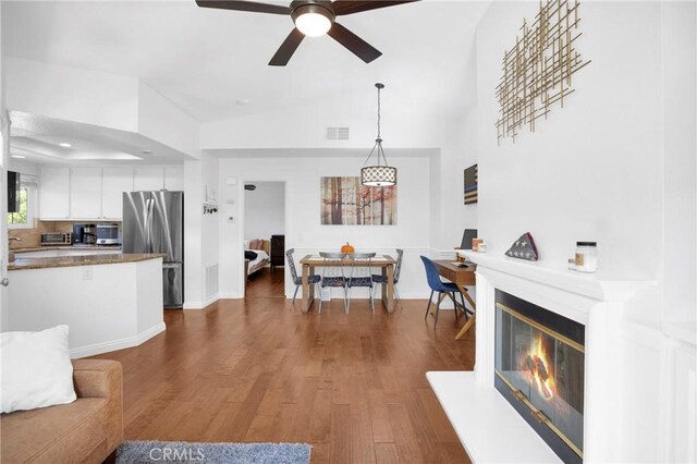 living room featuring ceiling fan, dark hardwood / wood-style floors, and vaulted ceiling