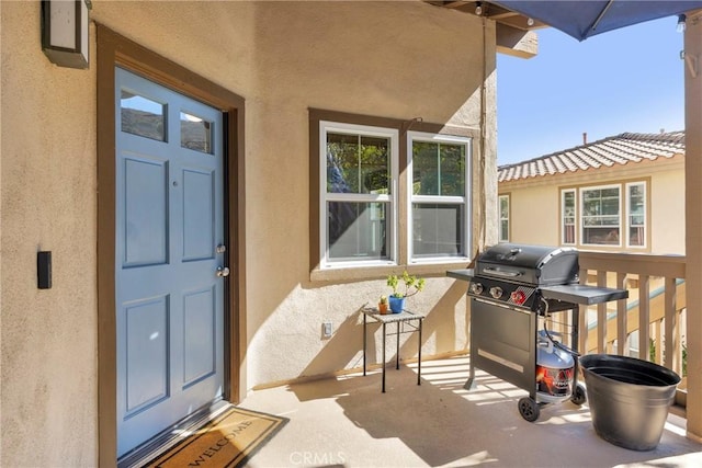 view of exterior entry with a tile roof and stucco siding