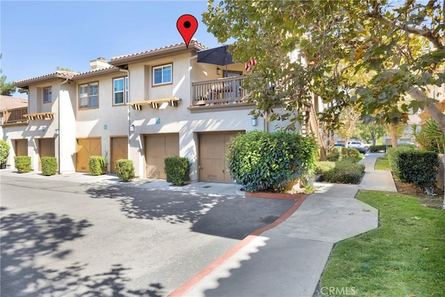 multi unit property featuring stucco siding, driveway, a garage, and a chimney