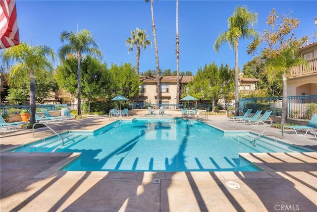 view of swimming pool featuring a patio and fence