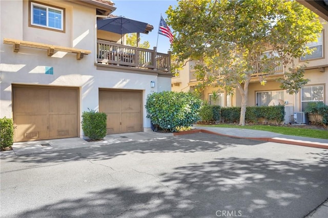 multi unit property featuring central AC unit, a garage, driveway, and stucco siding