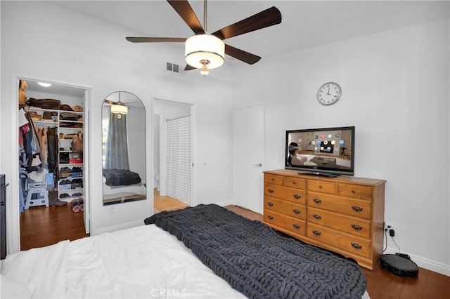 bedroom featuring a closet, ceiling fan, a walk in closet, and hardwood / wood-style floors