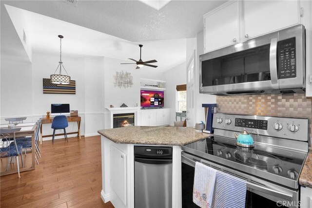 kitchen with a textured ceiling, white cabinets, decorative light fixtures, light hardwood / wood-style flooring, and stainless steel appliances