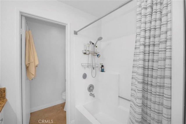 bathroom with tile patterned flooring, toilet, baseboards, and shower / bath combo