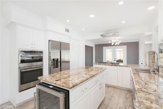 kitchen featuring a kitchen island, appliances with stainless steel finishes, white cabinetry, sink, and crown molding