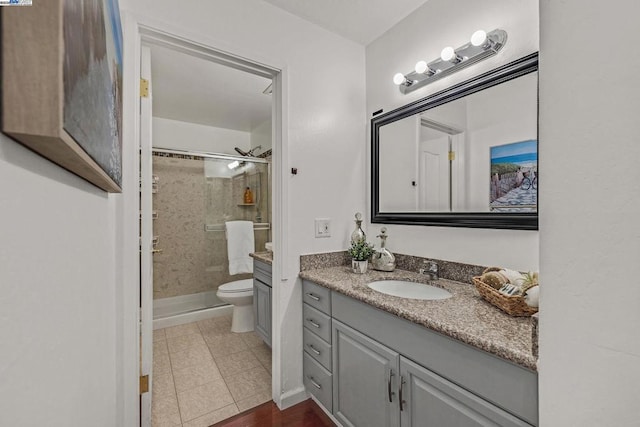 bathroom with tiled shower, vanity, toilet, and tile patterned floors