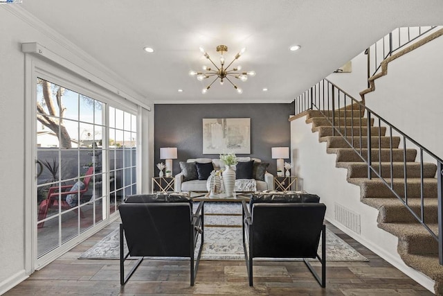 living room with hardwood / wood-style flooring, ornamental molding, and a notable chandelier