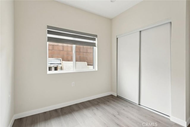 unfurnished bedroom featuring light hardwood / wood-style flooring and a closet