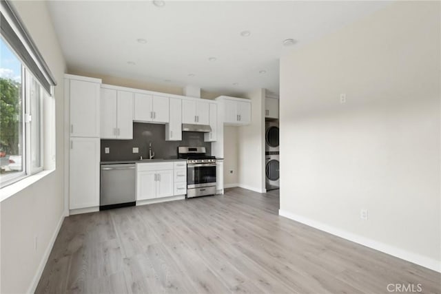 kitchen featuring stacked washer and dryer, white cabinetry, tasteful backsplash, stainless steel appliances, and light hardwood / wood-style floors