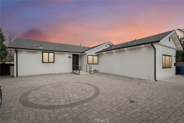 back house at dusk with a patio area