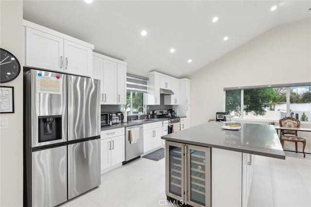 kitchen featuring vaulted ceiling, a kitchen island, appliances with stainless steel finishes, white cabinetry, and sink