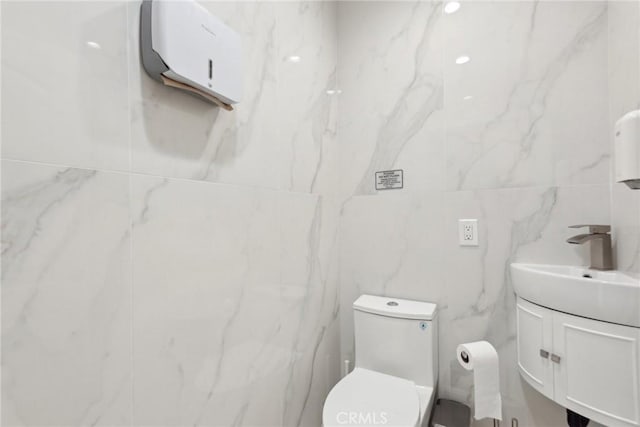 bathroom featuring vanity, toilet, and tile walls