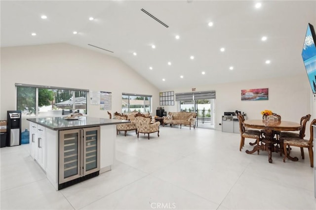 kitchen featuring wine cooler, high vaulted ceiling, a kitchen island, and white cabinets