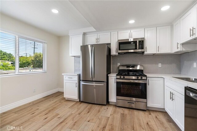 kitchen with white cabinets, appliances with stainless steel finishes, and light hardwood / wood-style flooring