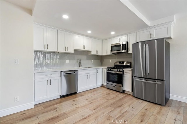 kitchen with light wood-type flooring, appliances with stainless steel finishes, sink, and white cabinetry