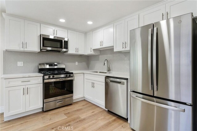 kitchen with sink, white cabinets, stainless steel appliances, and light wood-type flooring