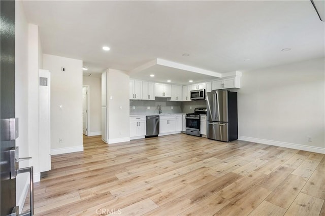 kitchen with appliances with stainless steel finishes, decorative backsplash, light hardwood / wood-style floors, and white cabinets