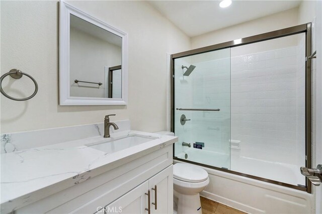 full bathroom with toilet, tile patterned flooring, enclosed tub / shower combo, and vanity