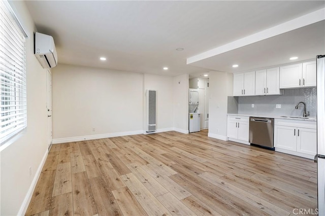 kitchen featuring white cabinetry, stacked washer and dryer, sink, a wall unit AC, and stainless steel dishwasher