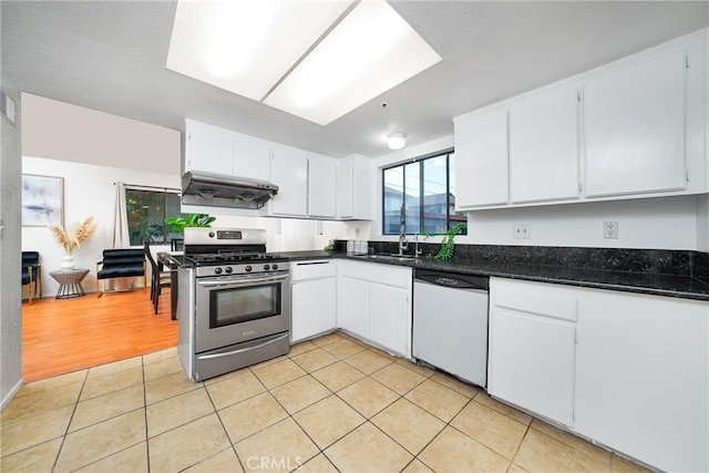 kitchen featuring exhaust hood, light tile patterned floors, white cabinetry, gas stove, and dishwashing machine