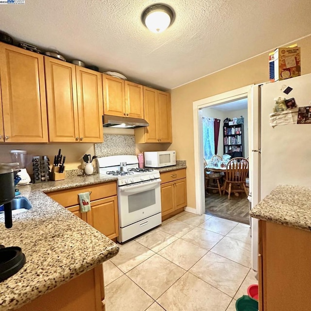 kitchen featuring light tile patterned flooring, white appliances, light stone countertops, and a textured ceiling