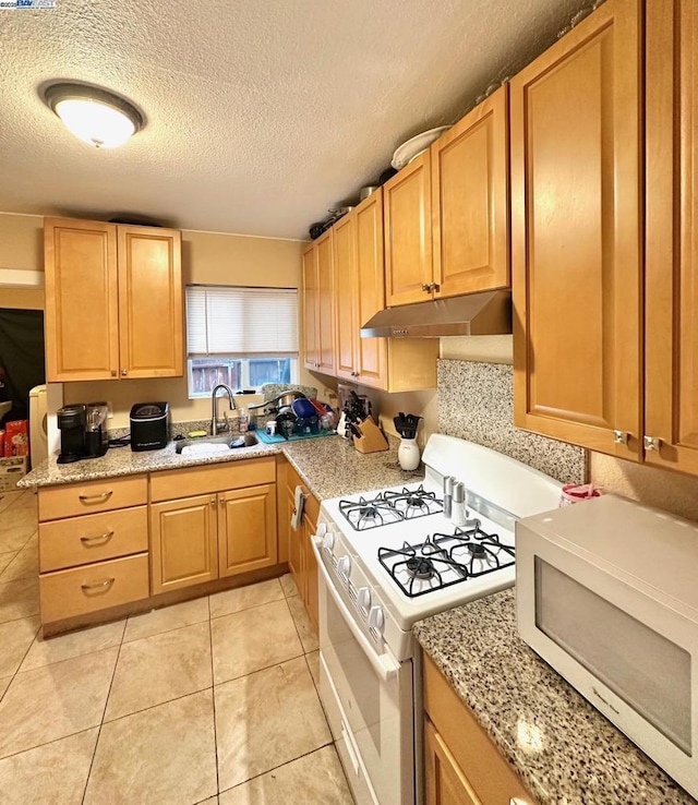 kitchen featuring light tile patterned flooring, sink, light stone counters, a textured ceiling, and white gas range oven