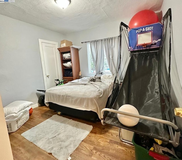 bedroom with wood-type flooring and a textured ceiling