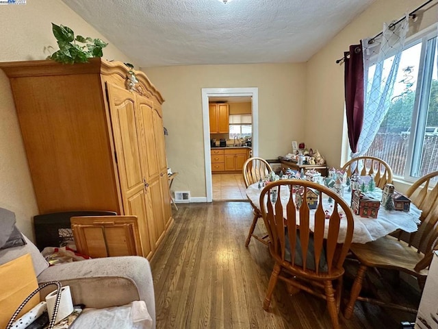 dining space featuring plenty of natural light, sink, hardwood / wood-style floors, and a textured ceiling