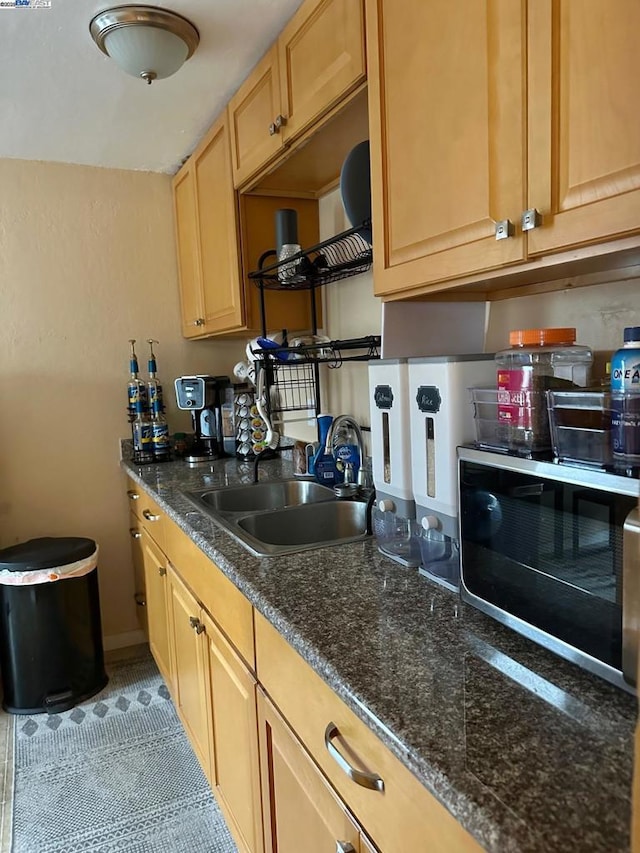 kitchen with tile patterned flooring, sink, and dark stone counters