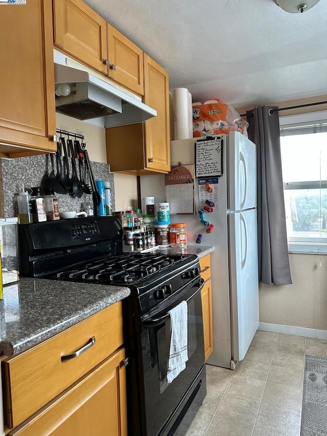 kitchen featuring black gas stove, light tile patterned floors, and dark stone counters