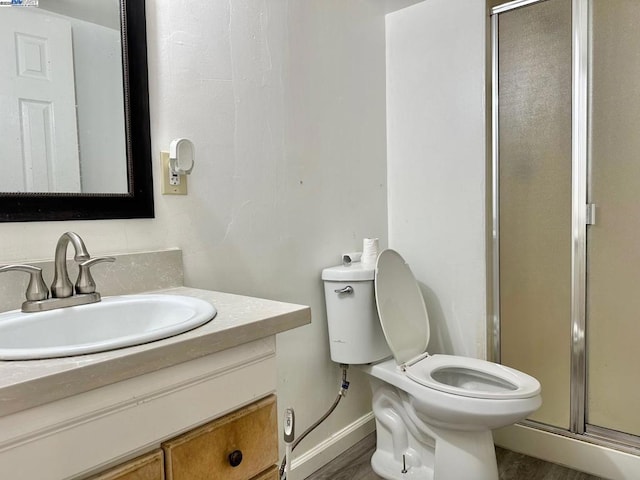 bathroom with vanity, hardwood / wood-style flooring, a shower with shower door, and toilet