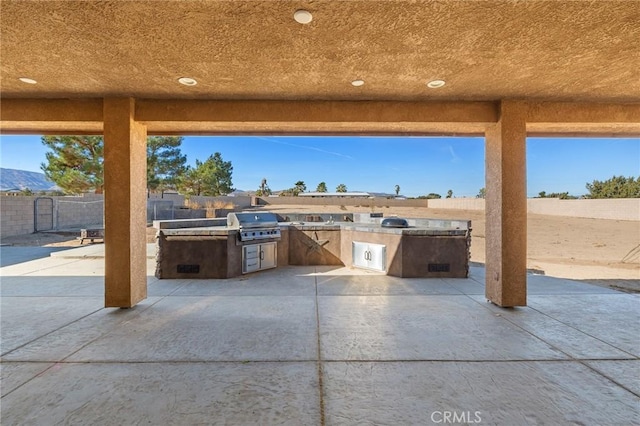 view of patio with exterior kitchen, a mountain view, and area for grilling