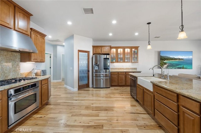 kitchen with appliances with stainless steel finishes, decorative backsplash, light stone countertops, pendant lighting, and sink