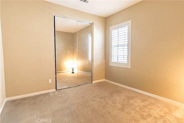 unfurnished bedroom with light carpet and a closet