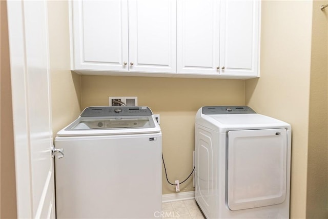 clothes washing area with washing machine and clothes dryer and cabinets